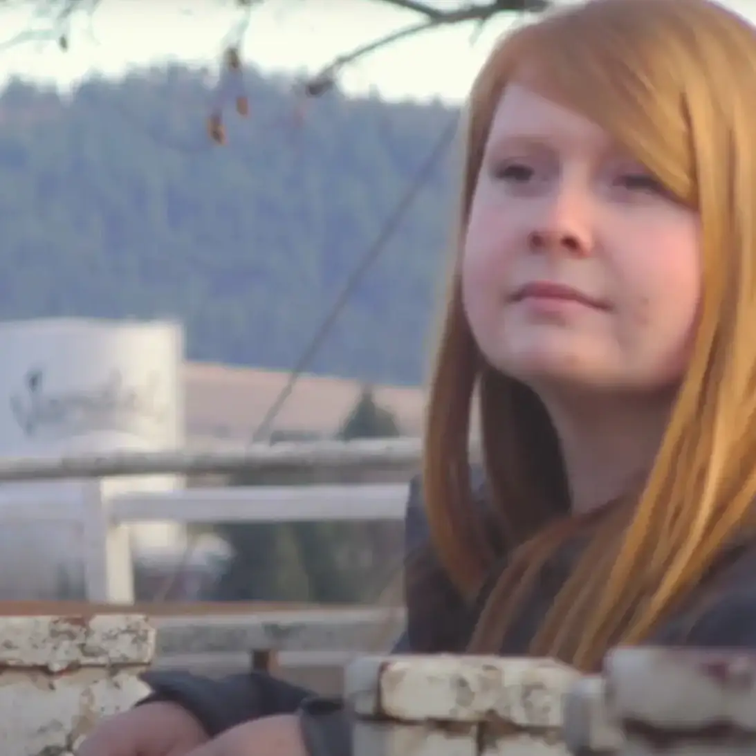 A woman leaning against a corral