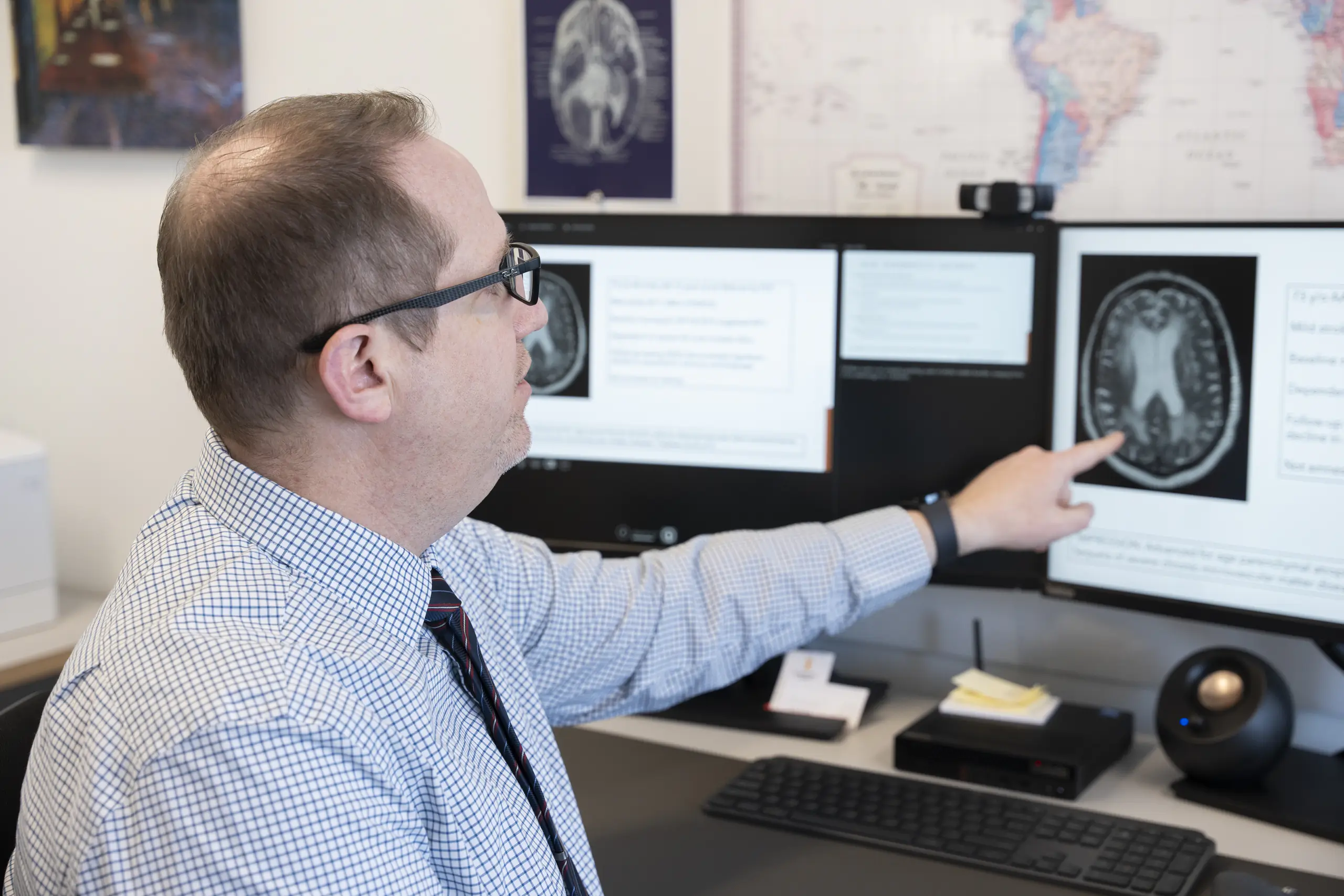 Professor Thomas Farrer points to a black and white brain scan on a computer screen.