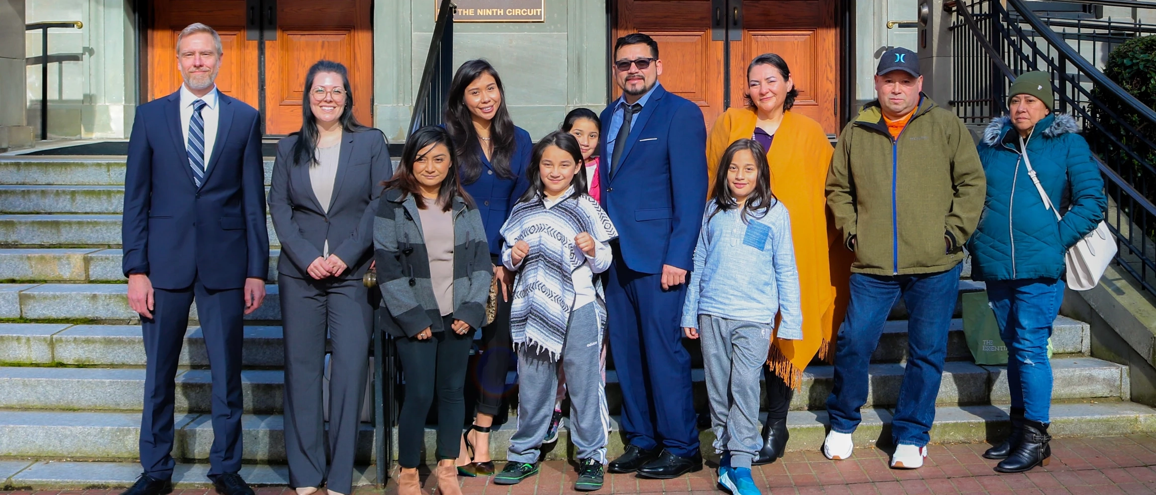 A group of people smiling in front of a building