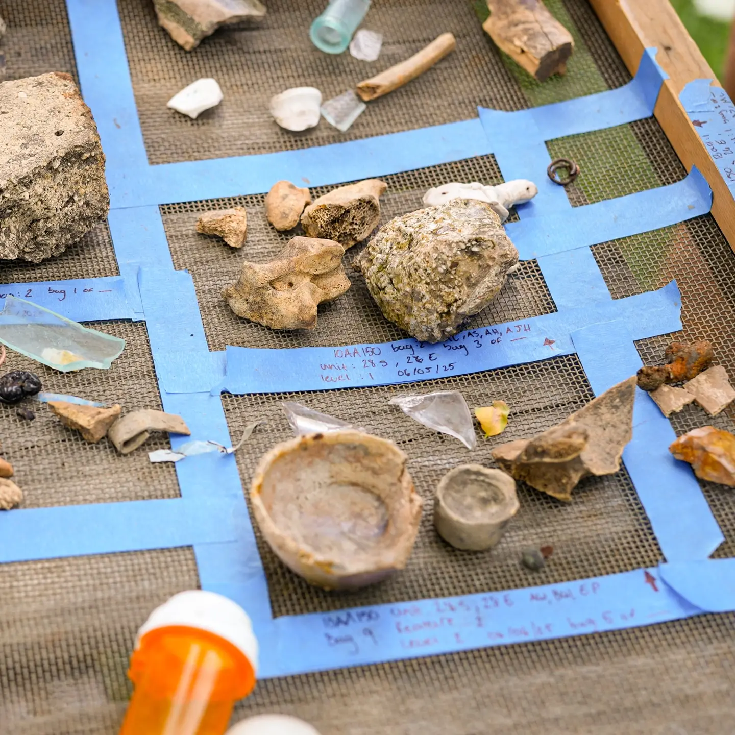Pieces of glass, metal and porcelain on a cloth with blue tape.