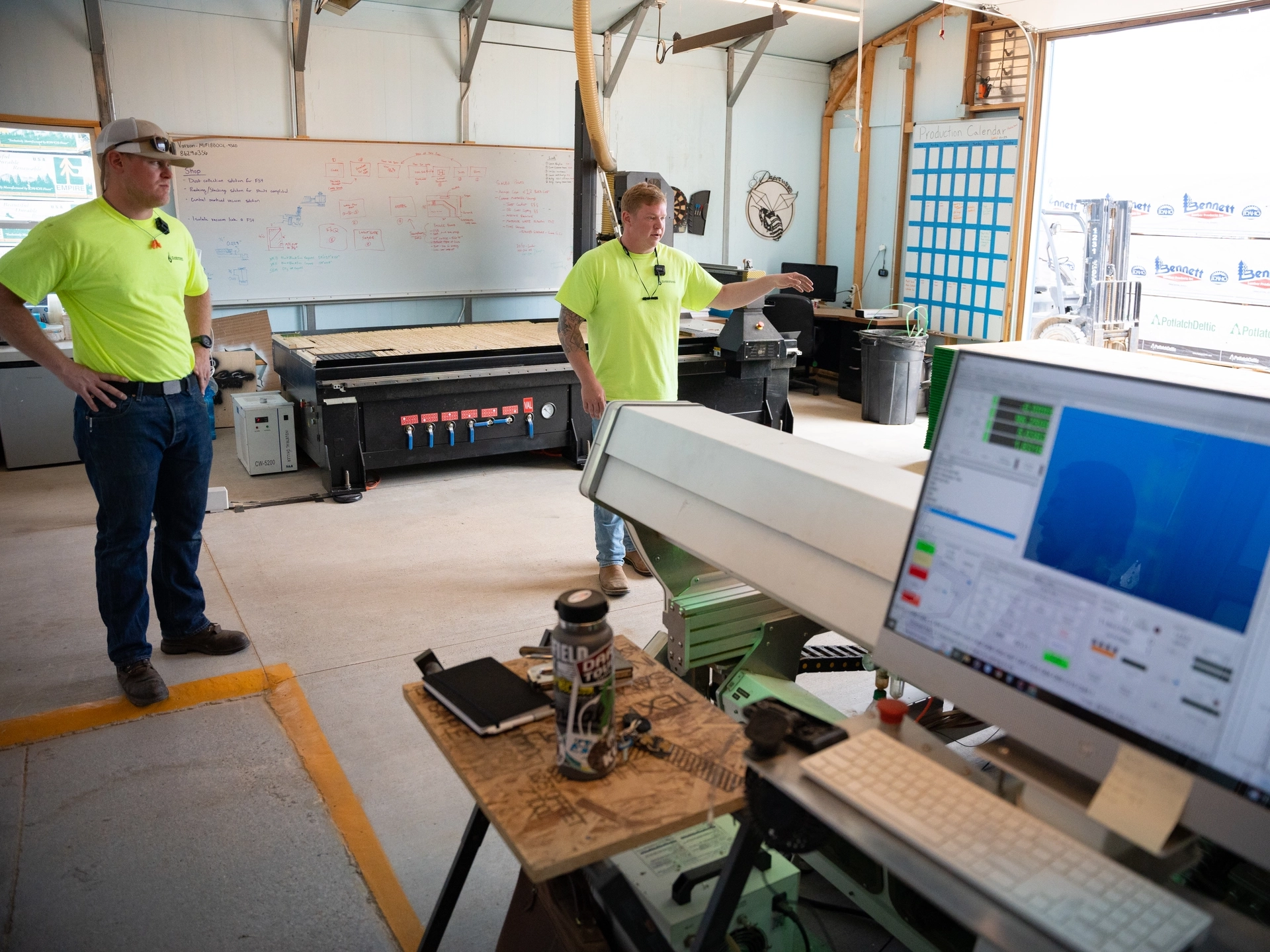 Flashpoint owners Nick Stoppello and Pat Churchman standing in their workshop, a large CNC machine and computer in the forefront