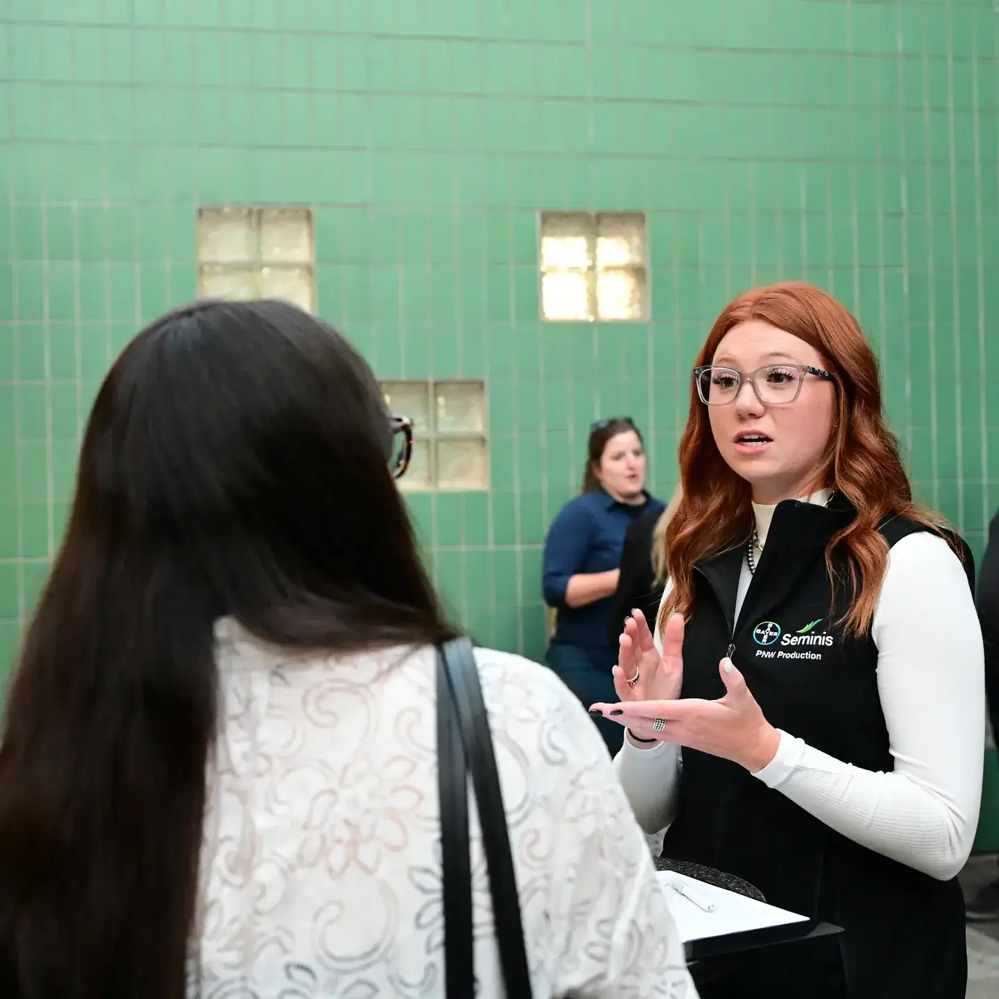A woman talking to another woman in a professional setting.