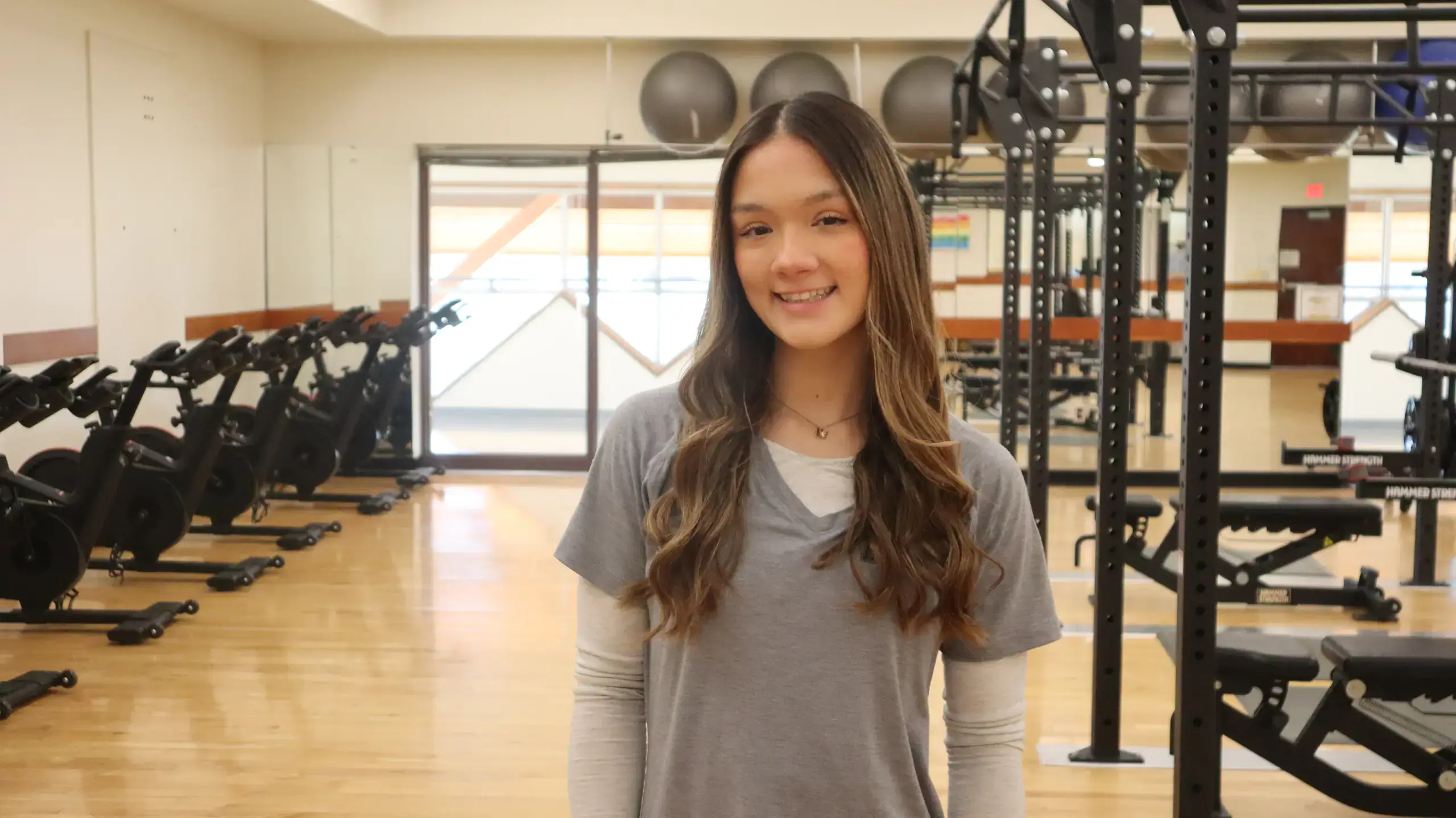 Gracie McClendon in gray shirt posing in weight room at Student Recreation Center.