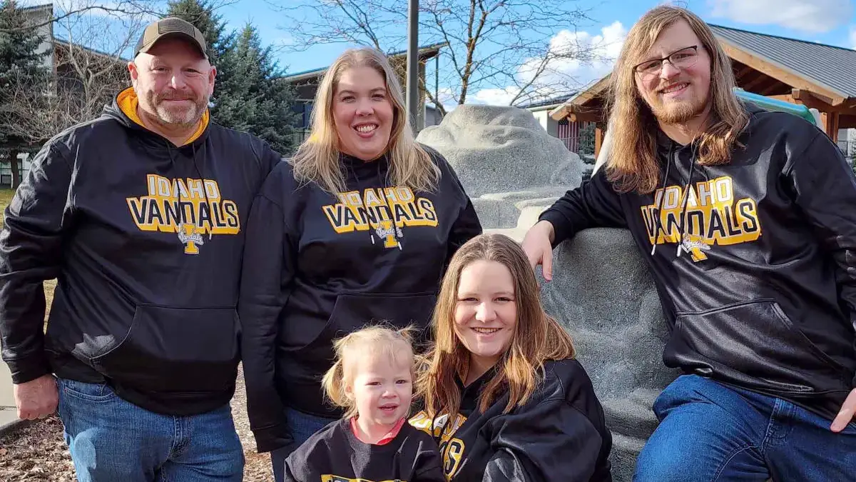 A family smiling while wearing Idaho Vandal sweatshirts