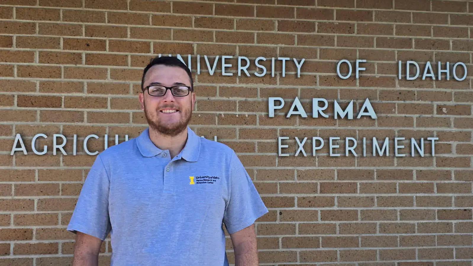 Marcelo Dimase stands by a brick wall.