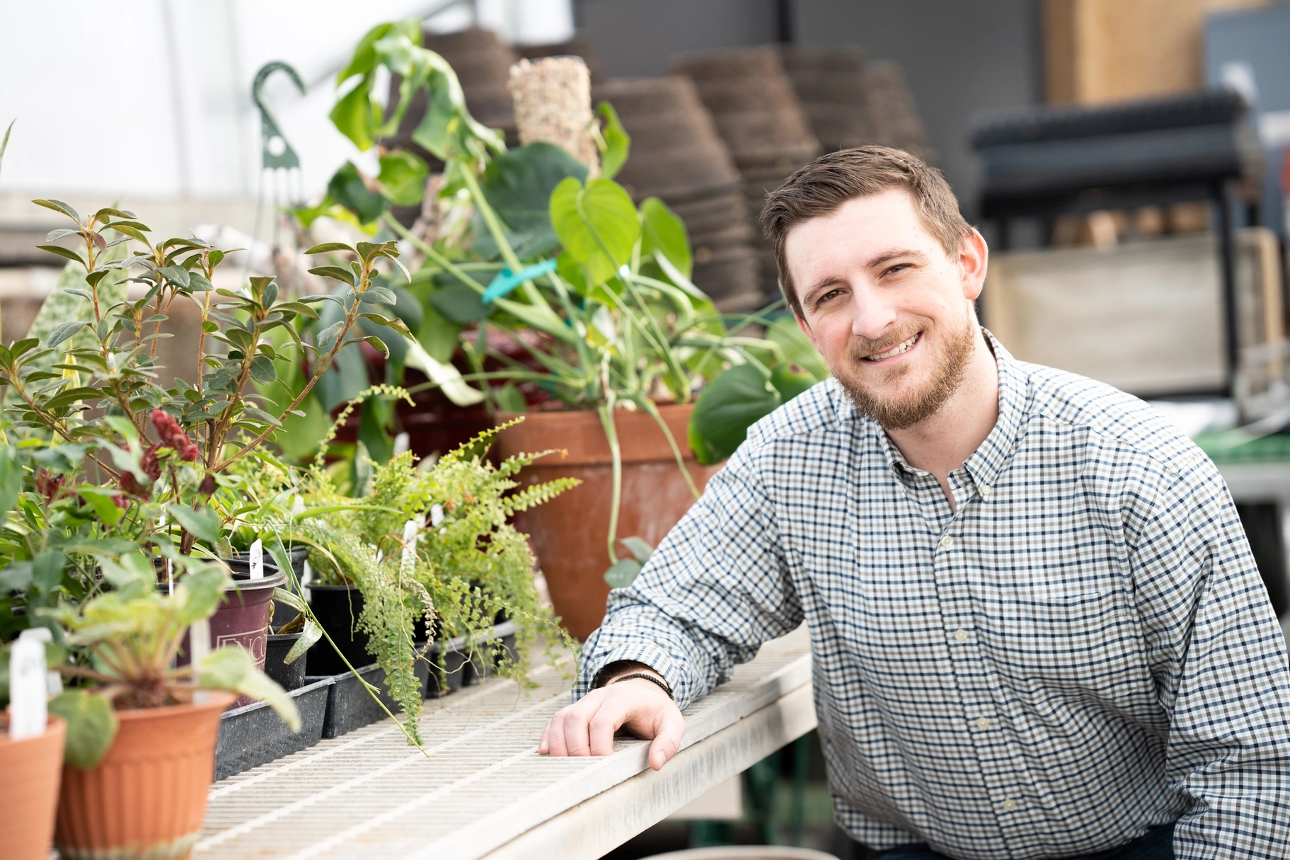 A portrait of a man in a greenhouse.
