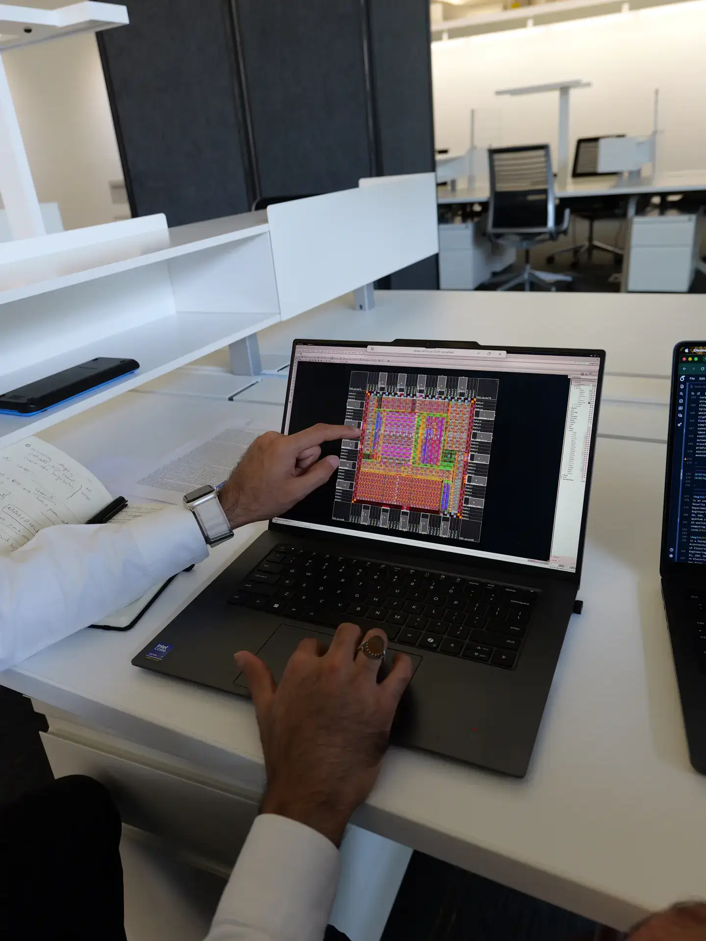 Person reviewing a semiconductor chip layout on a laptop in an office workspace
