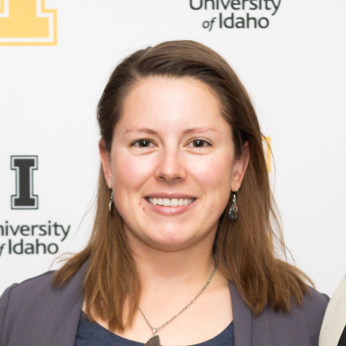 A woman smiling in front of a University of Idaho backdrop.
