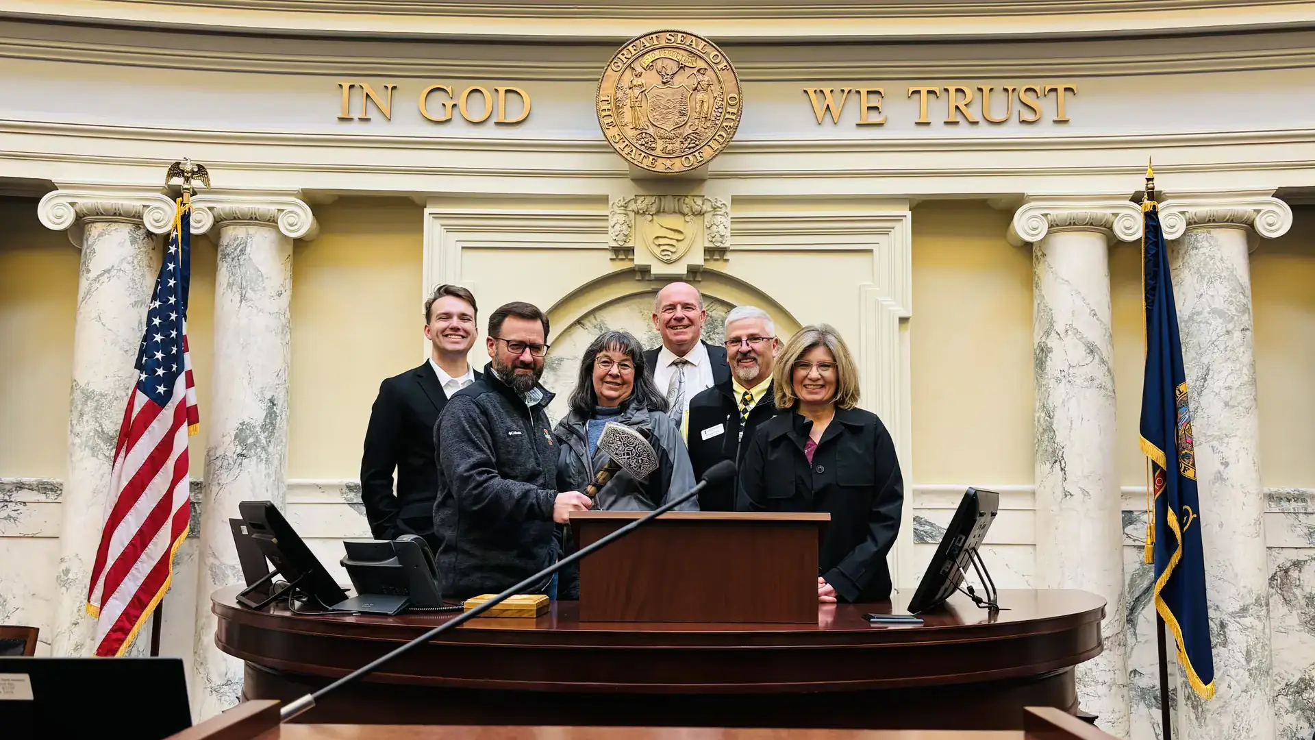 A group photo of men and women pose behind the speaker's chair.