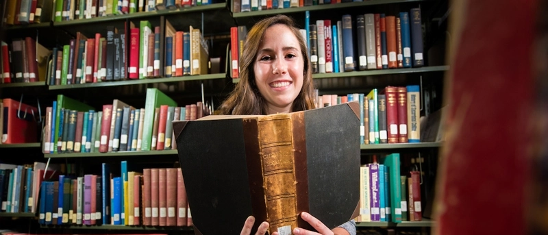 person holding open book in a library