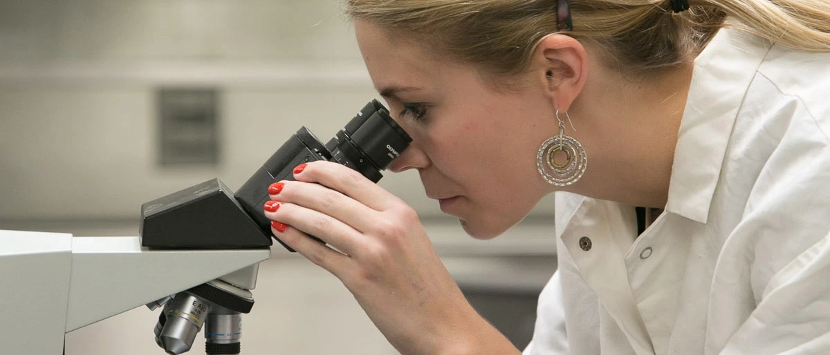 Woman studying microscope in food science laboratory