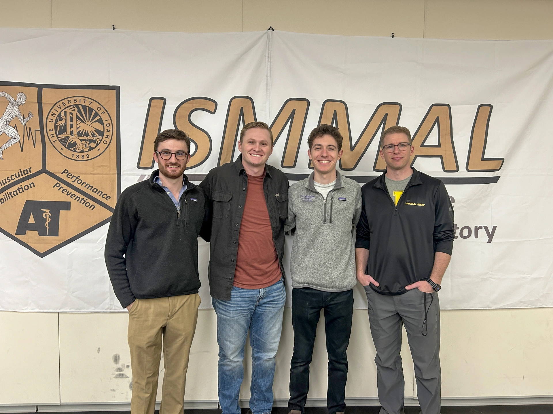 Graf Kirk, Kaden Kunz, John Wadner and Nick Martonick pose in front of an ISMMAL banner