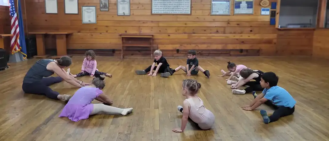 Young dancers stretch in group on floor