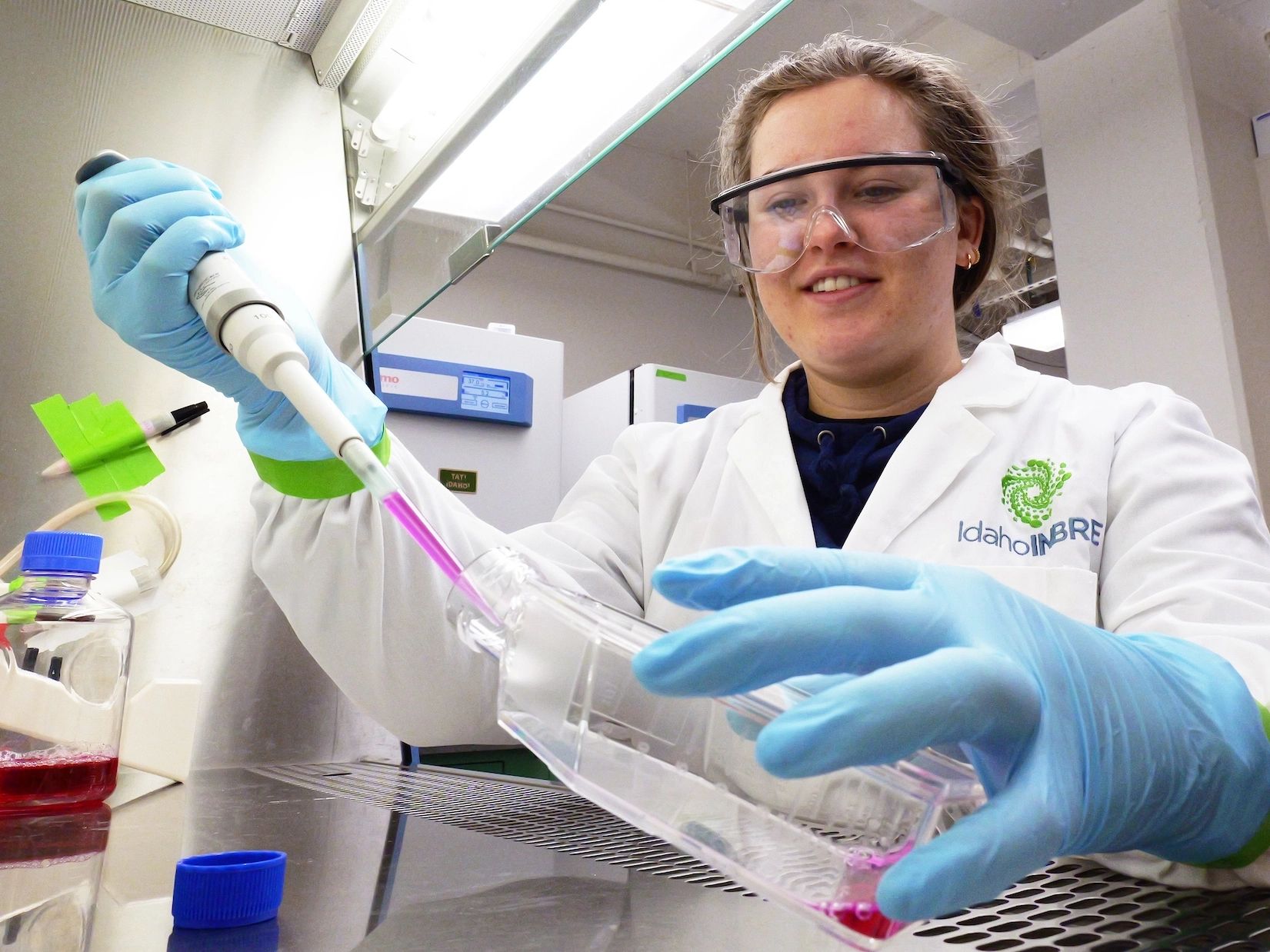  Grace Clair wear lab coat and readies cells for viewing under a microscope.