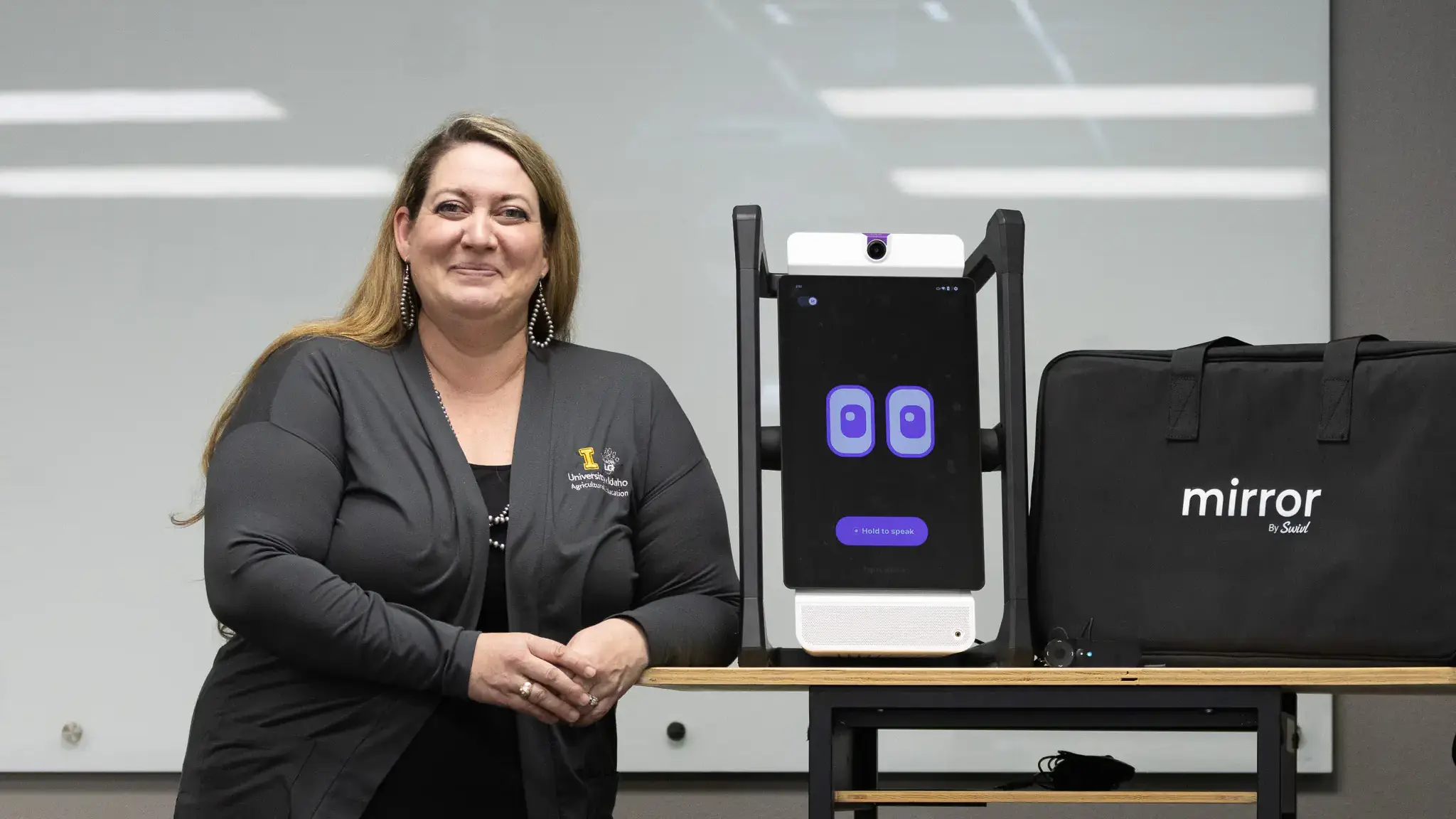 A woman poses with a robot, which has a flat screen with blinking eyes.