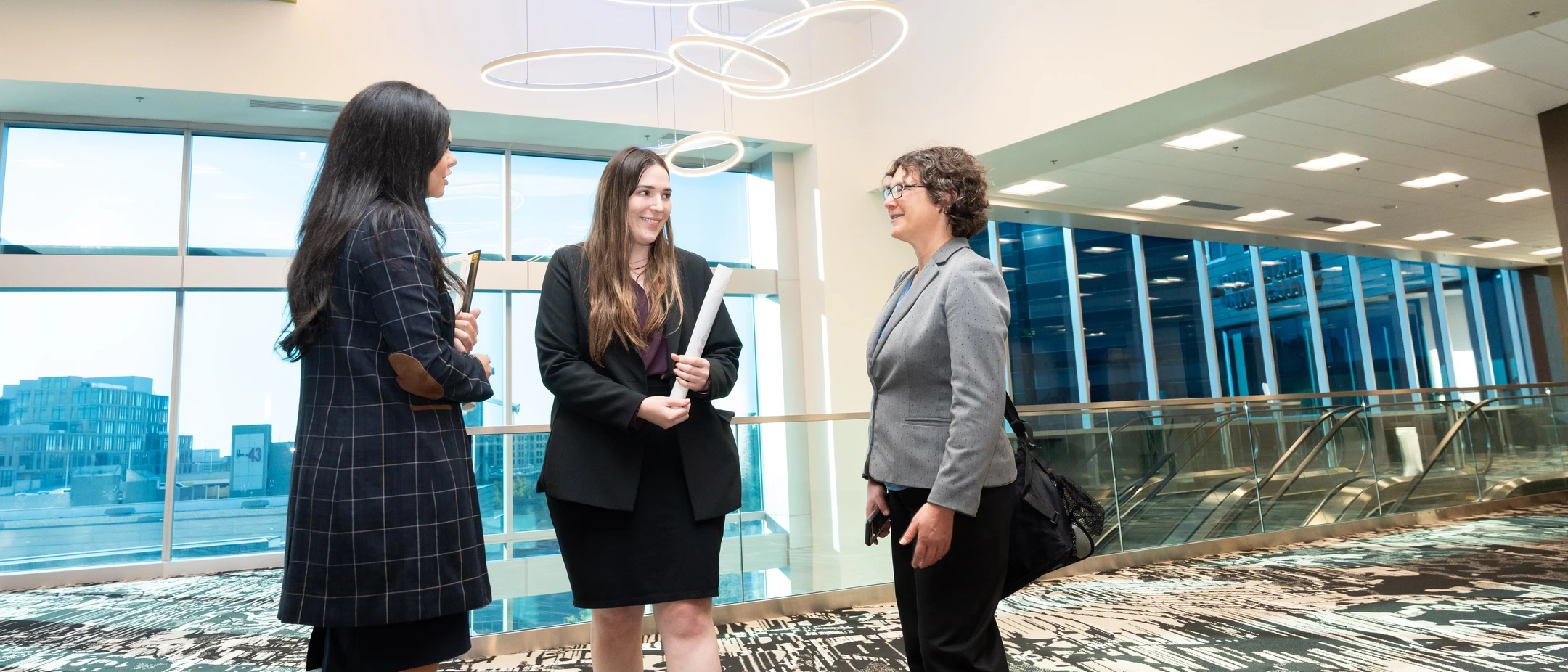 Three professionally dressed women standing in a circle talking