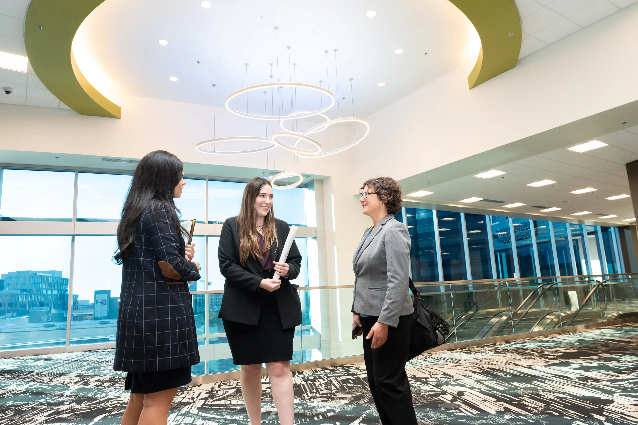 Three professionally dressed women standing in a circle talking