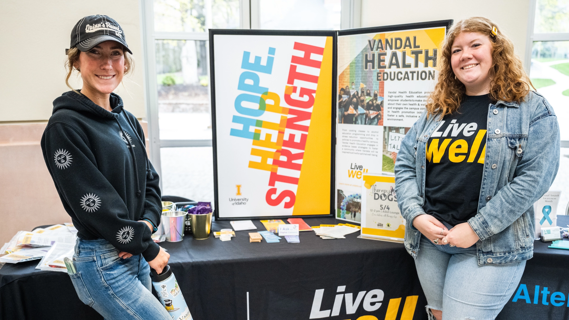 Two U of I students standing in front of a table display