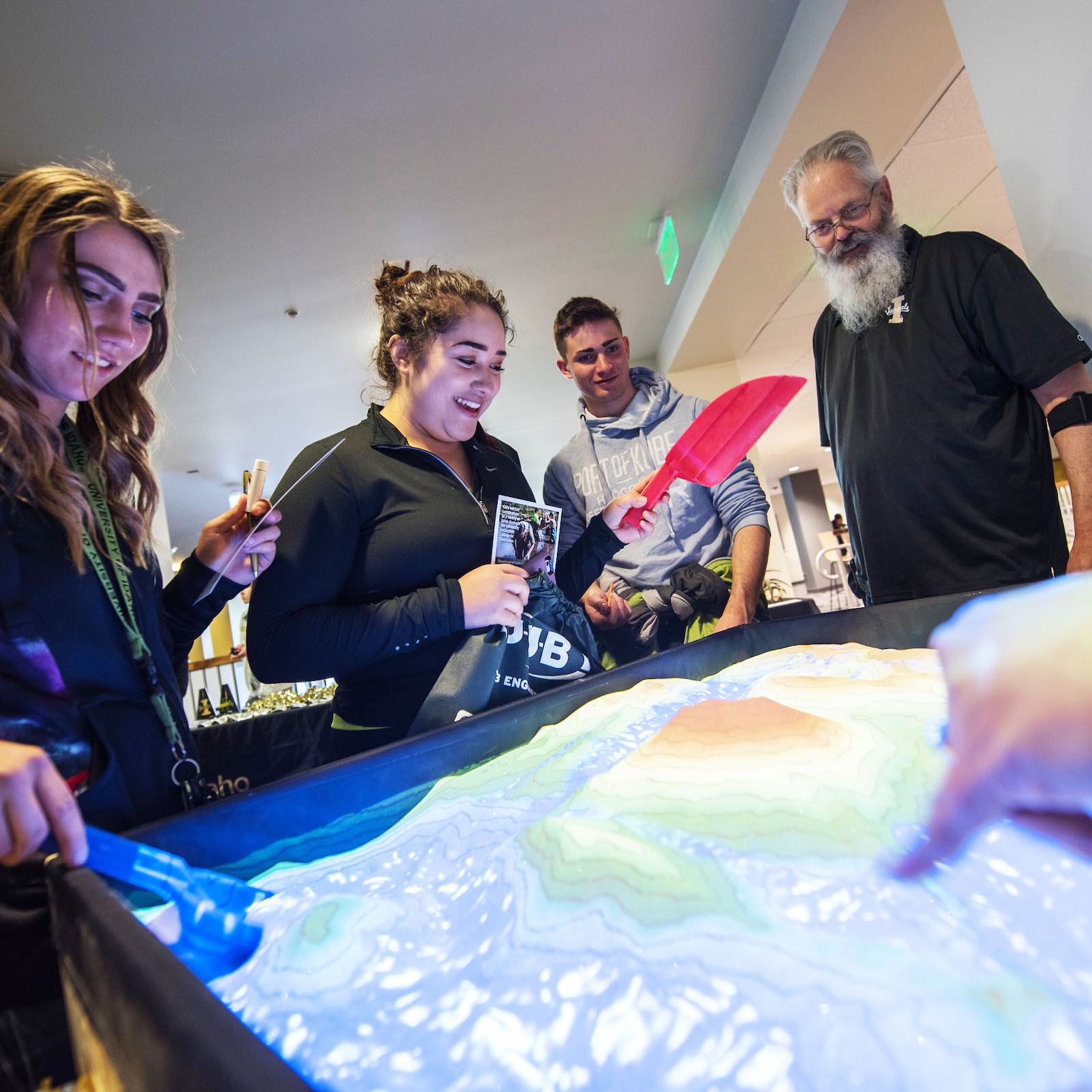 Students scoop sand in a simulator