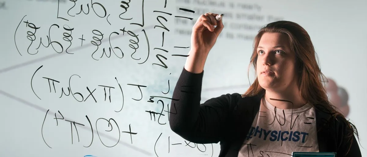 Woman student writing equations on board