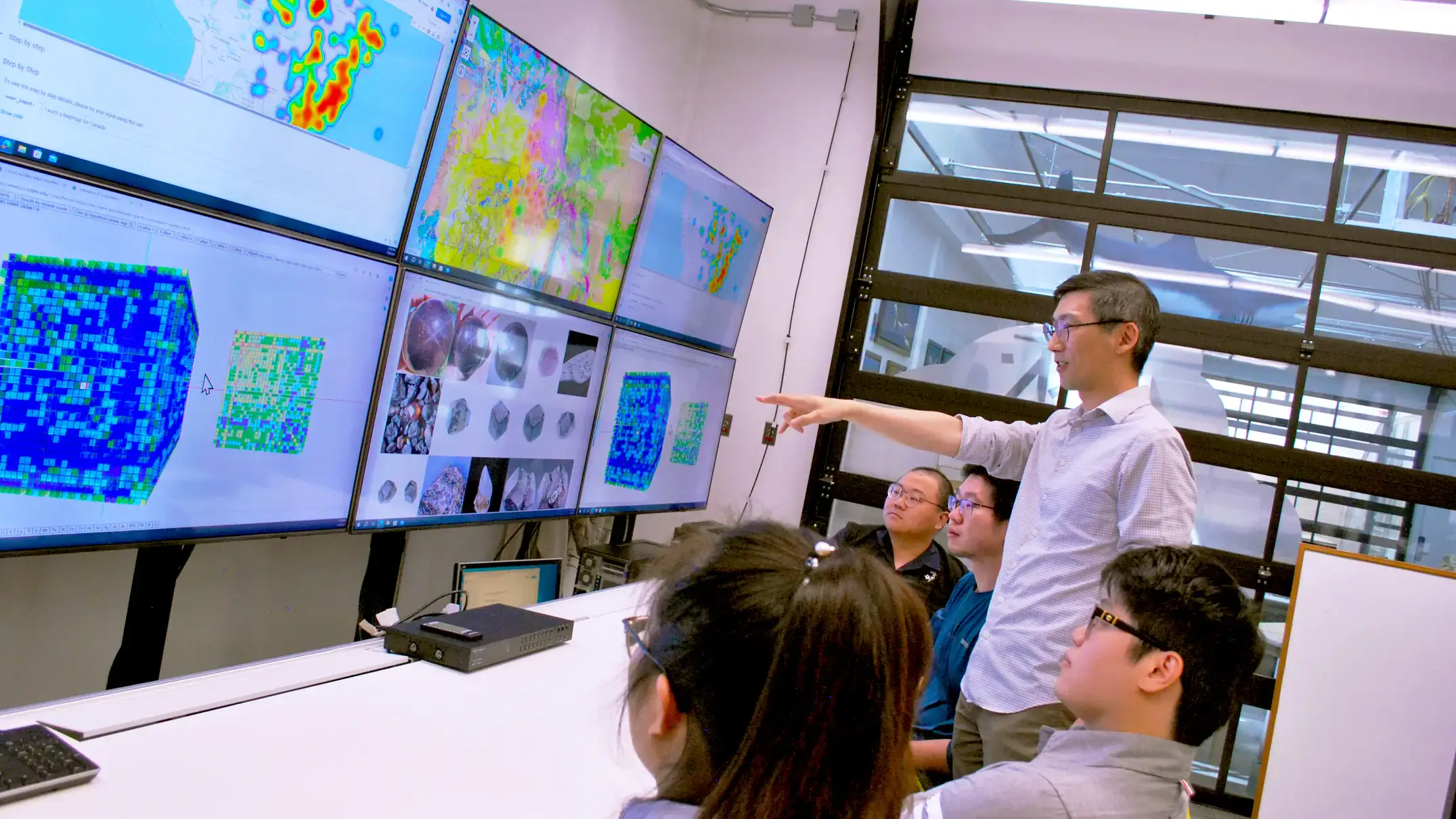 A man teaches students in front of screens.