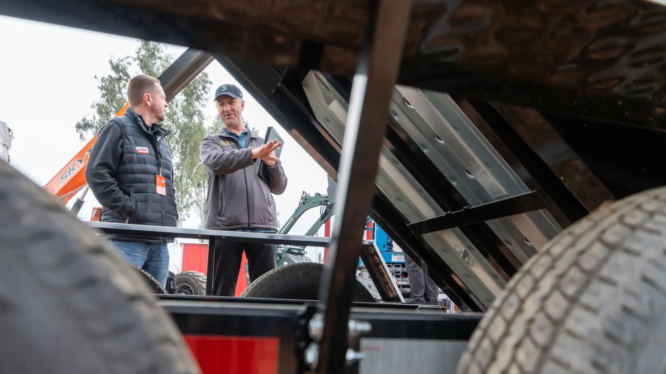 Two men talking near a piece of machinery.
