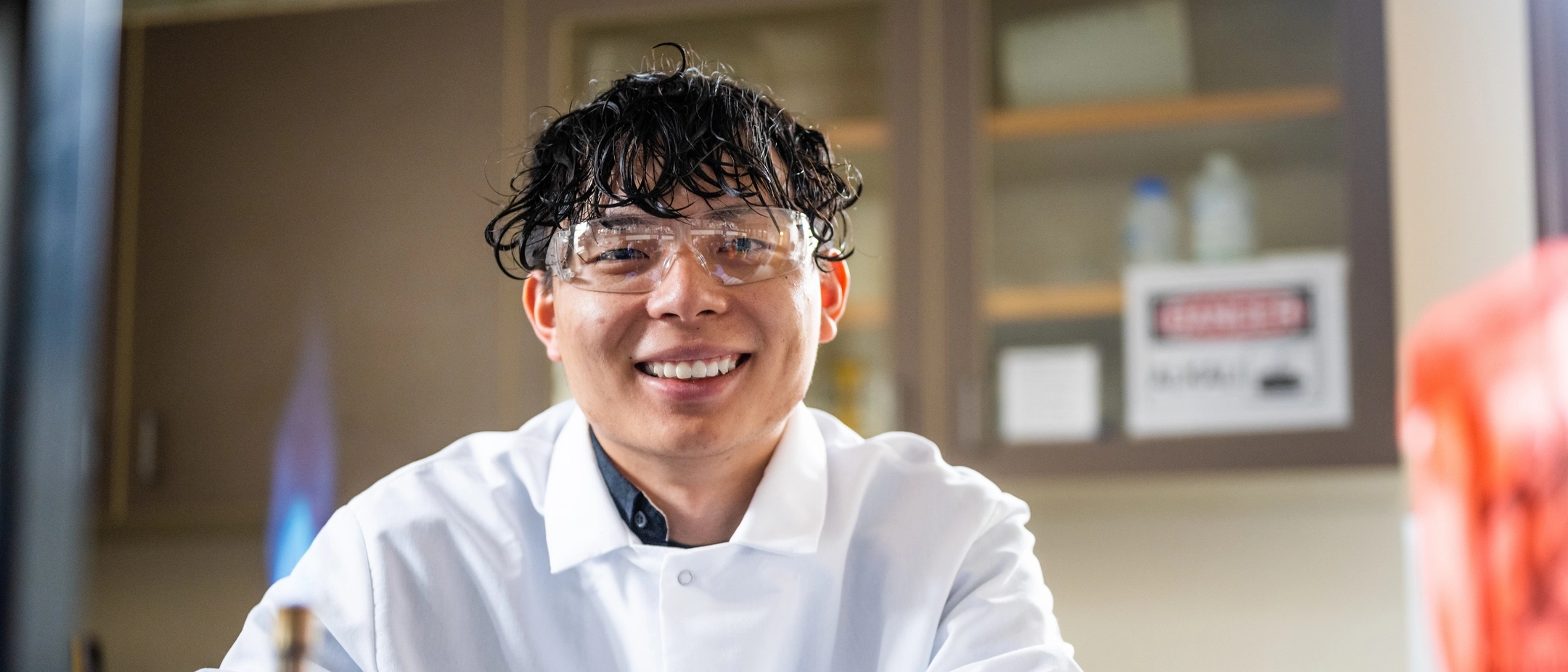 University of Idaho student Zhenhao (Victor) Zhong in a lab wearing a lab coat near chemistry equipment. . 