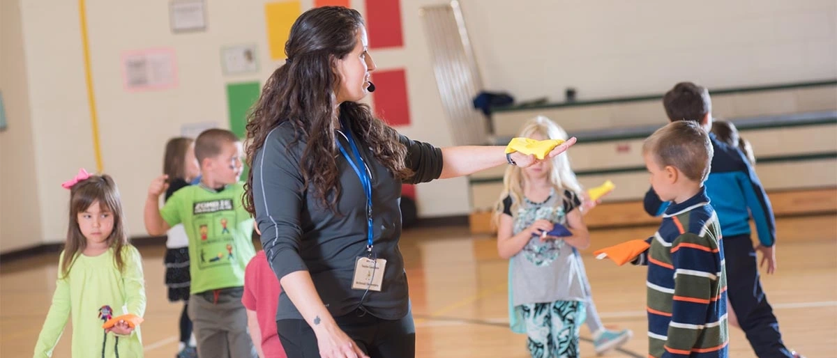student PE teacher showing an activity as school children play along