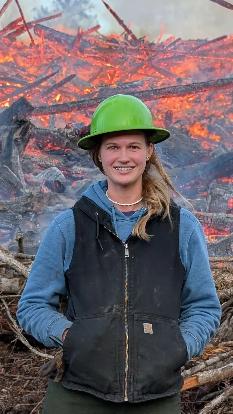 Maria Kinne smiles in front of a controlled fire
