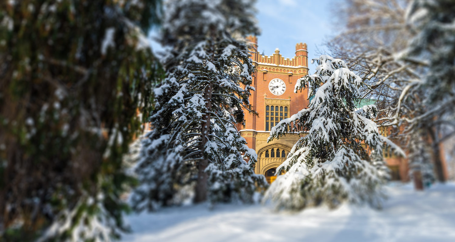 U of I Administration building surrounded by evergreen trees covered in snow.