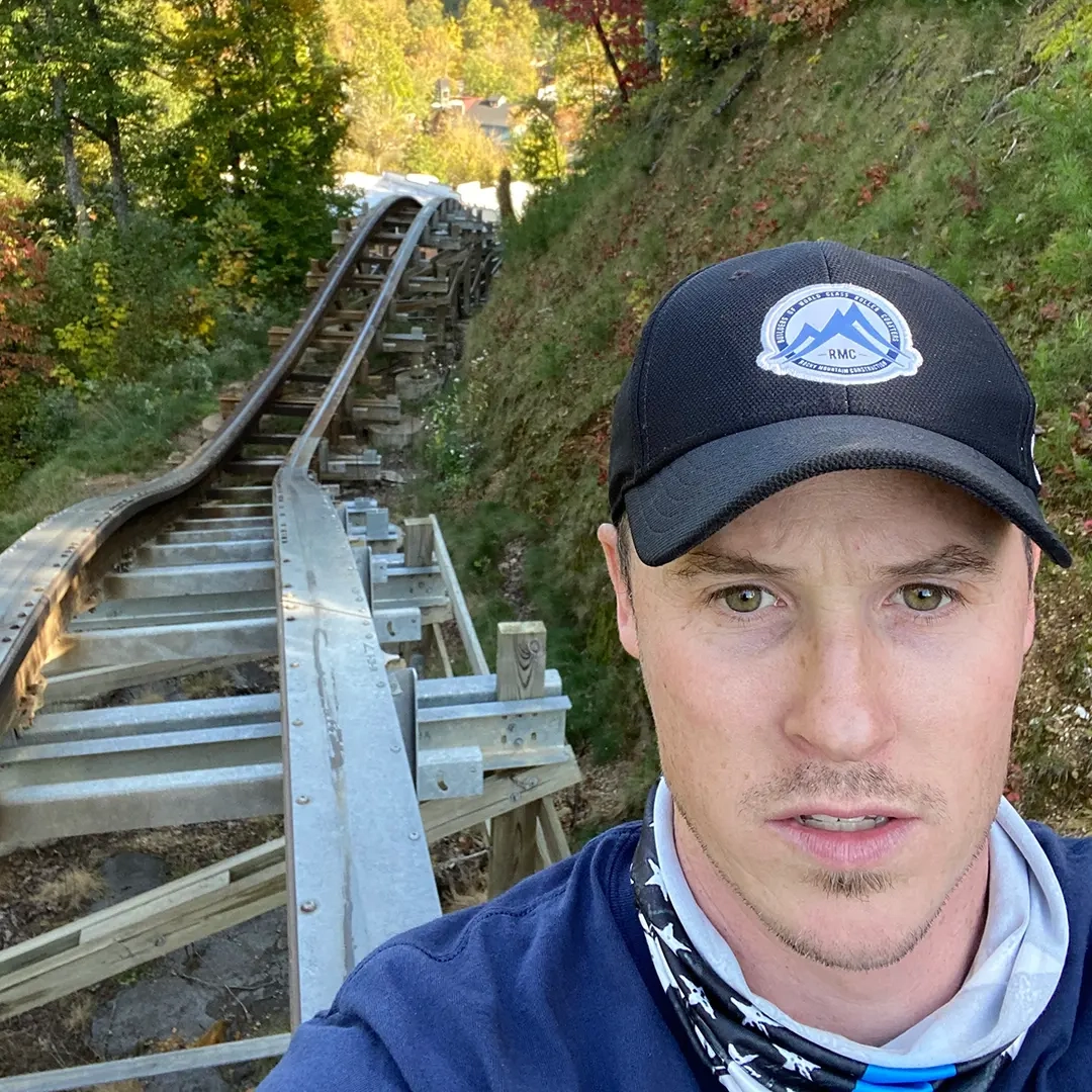 A man stands in front of broken-down wooden coaster track