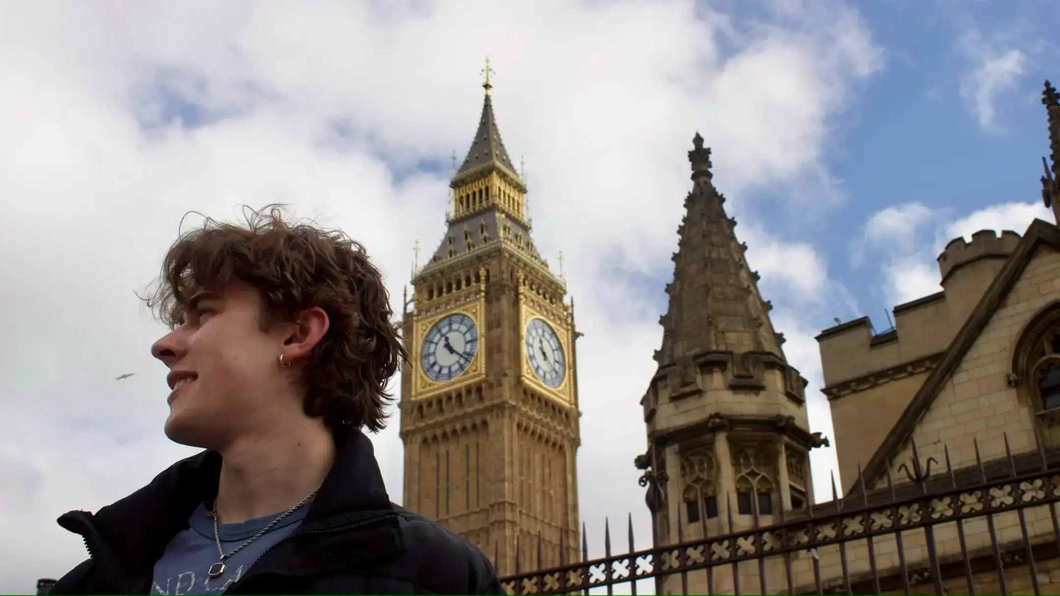 A low-angle shot of a man standing in front of the Big Ben clocktower.  