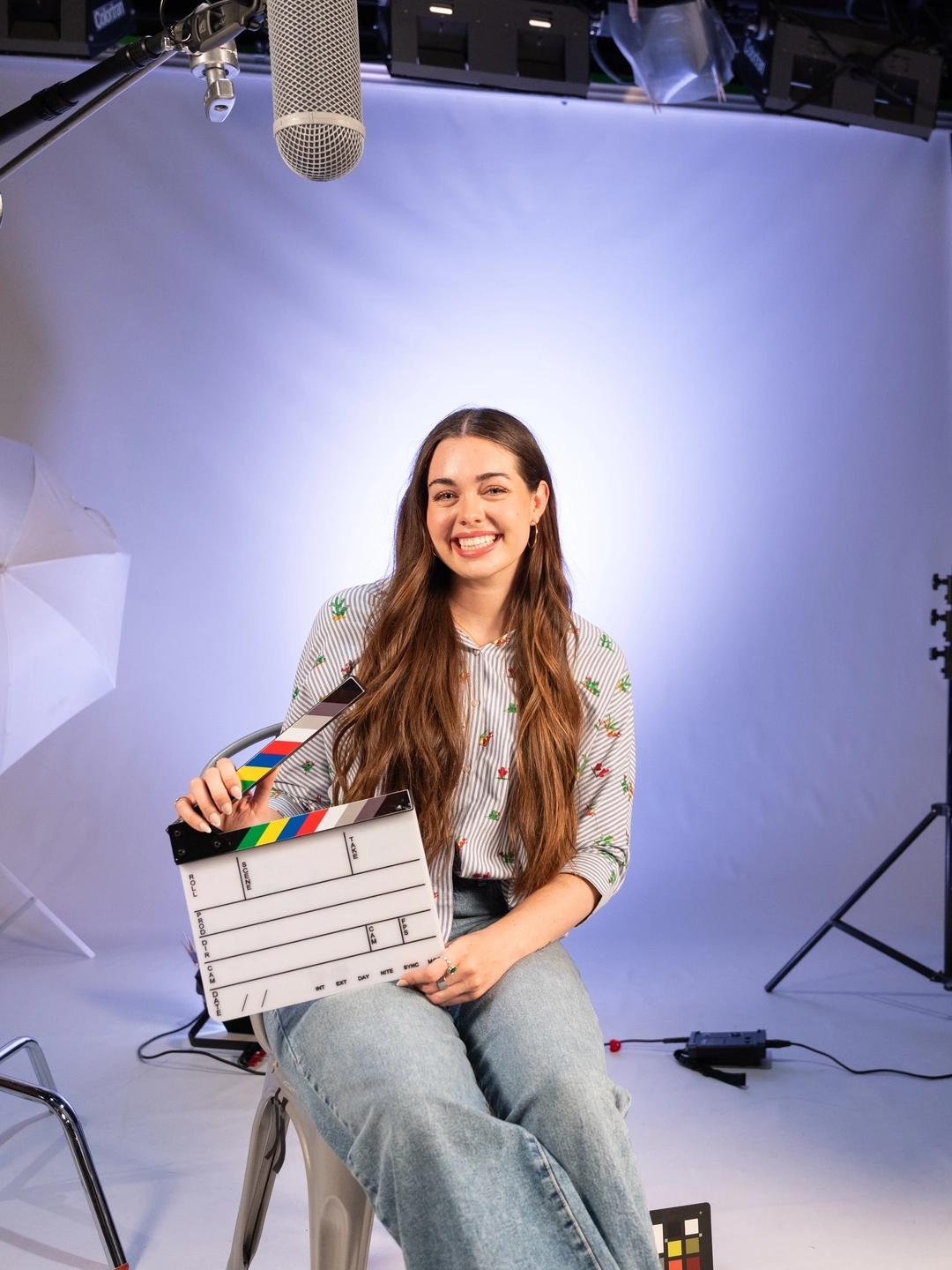 person sitting and holding a movie clacker on their lap within studio environment