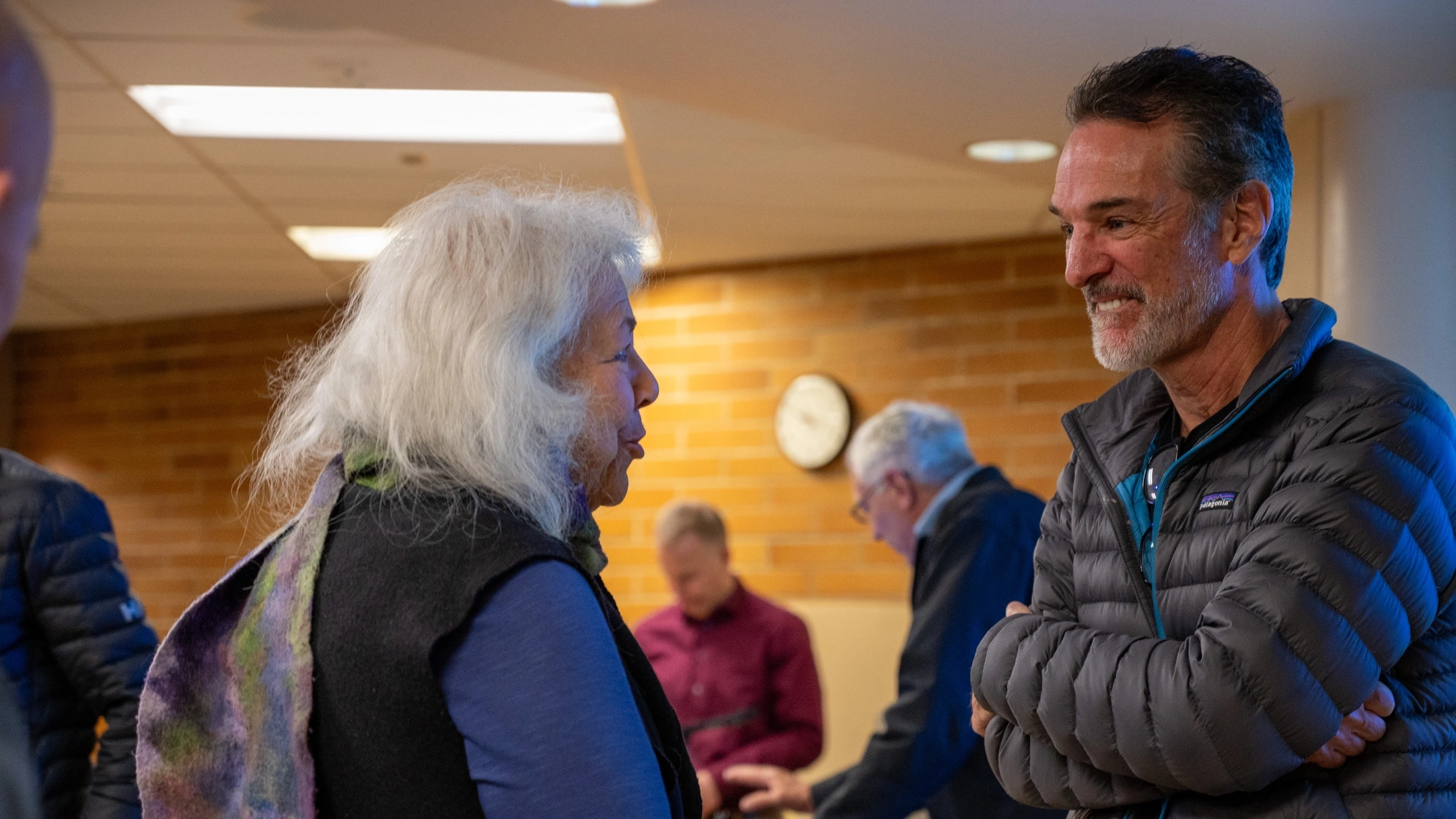 Tom Mueller smiles as he listens to a woman after his presentation