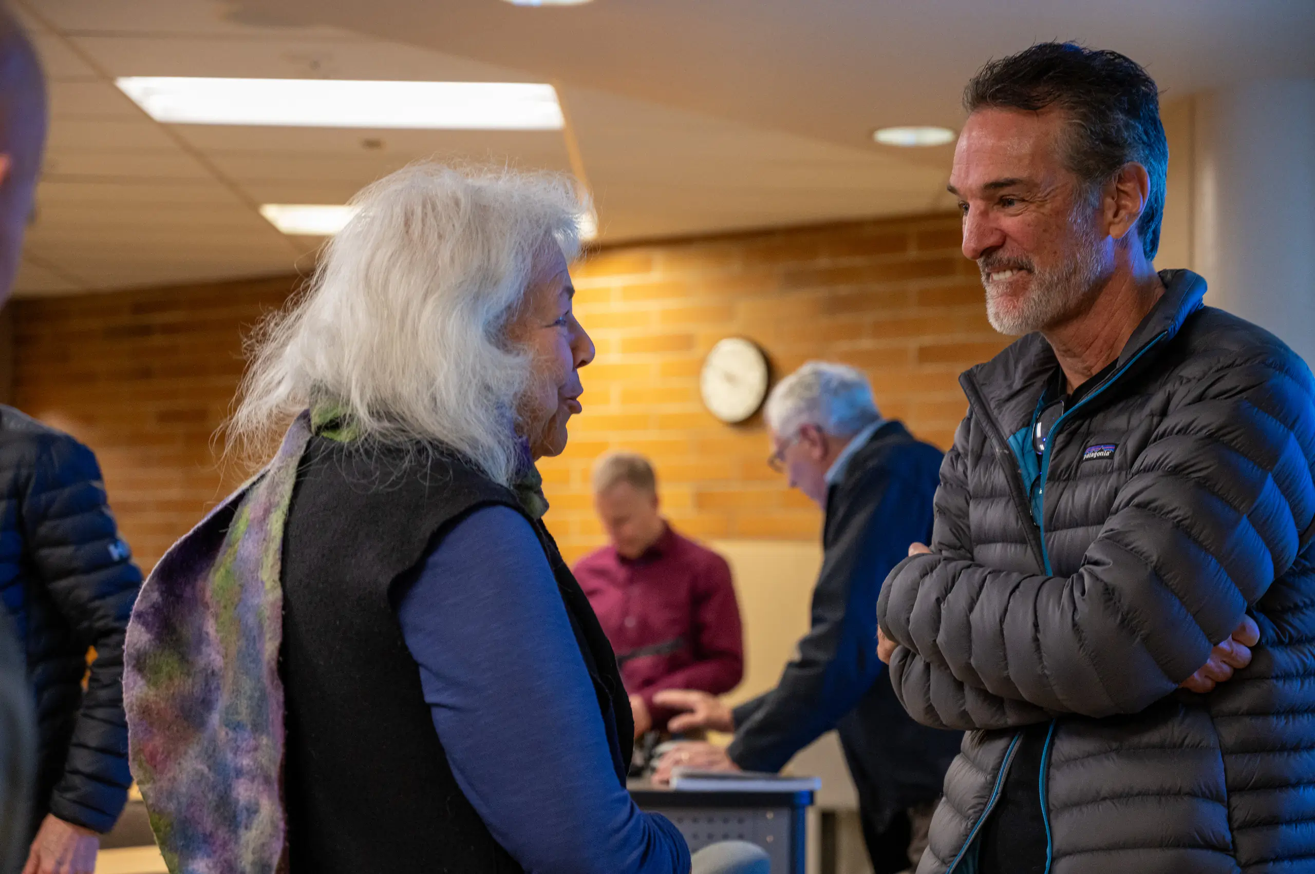 Tom Mueller smiles as he listens to a woman after his presentation