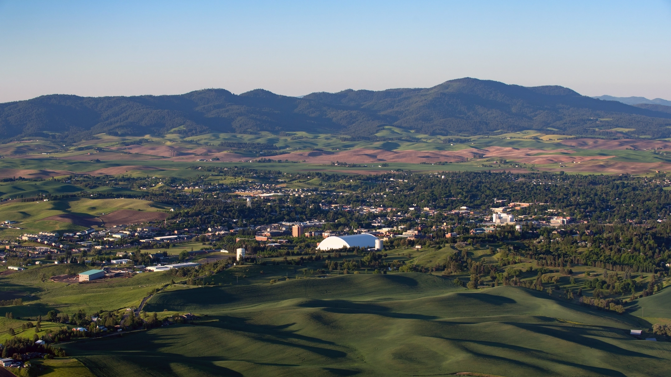Aerial view of Moscow, ID with lush greenery and mountains in the background