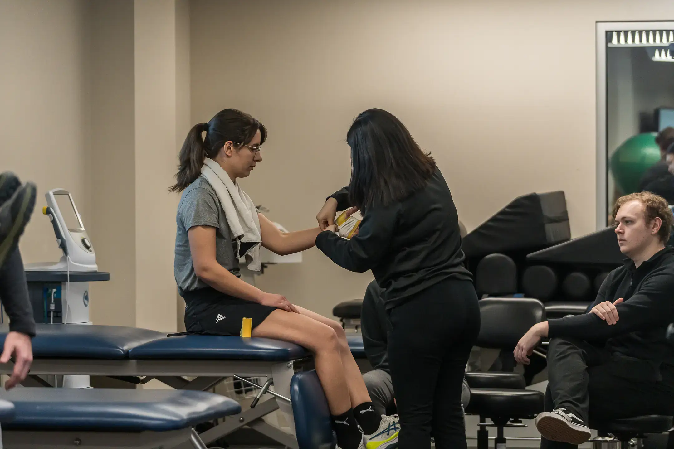Woman wraps wrist with bandage of another woman.