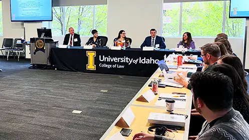 Speakers convene at a  long panel in front of an audience