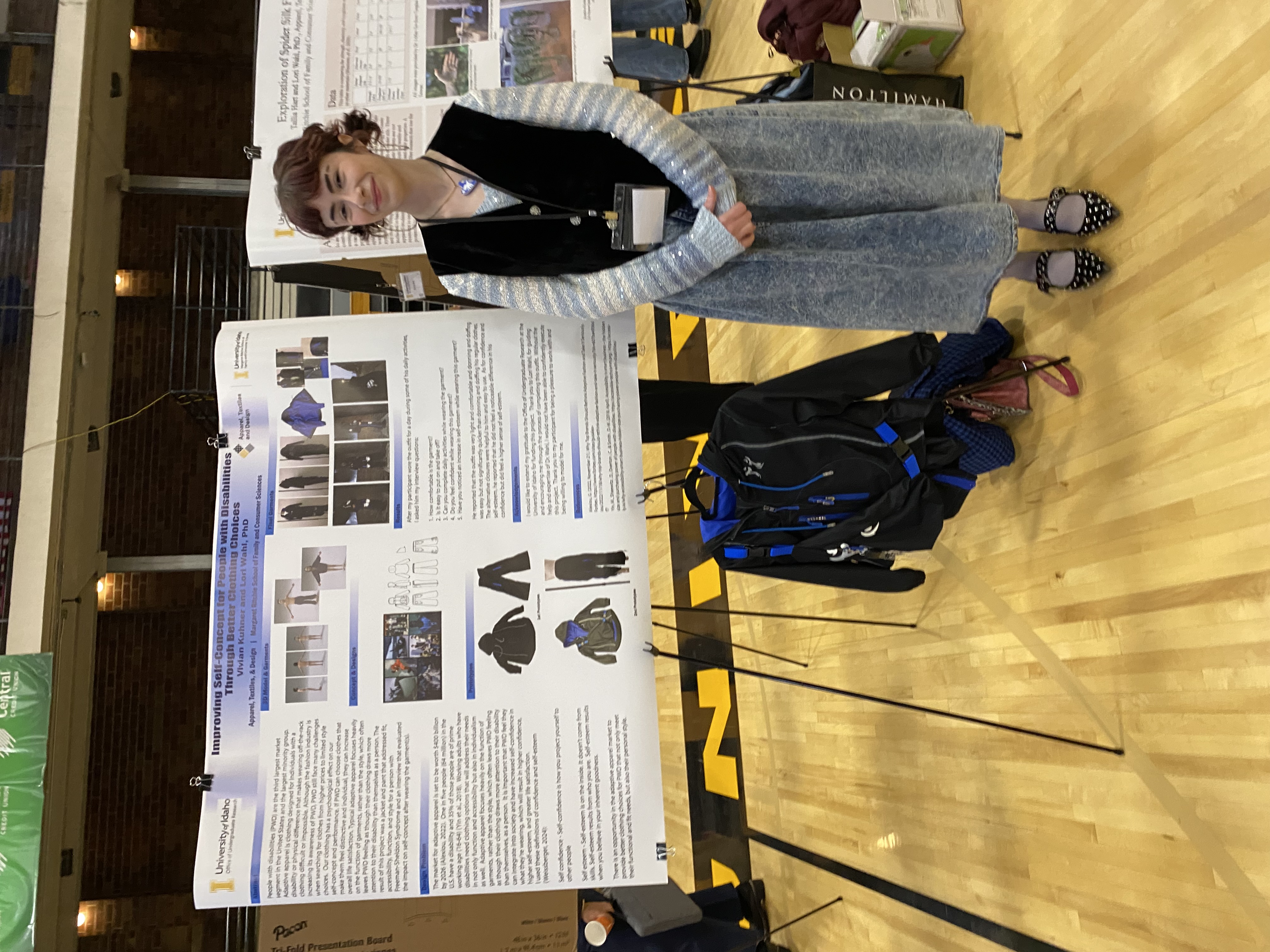 A person stands next to a research poster presentation on clothing design for people with disabilities at a university event.