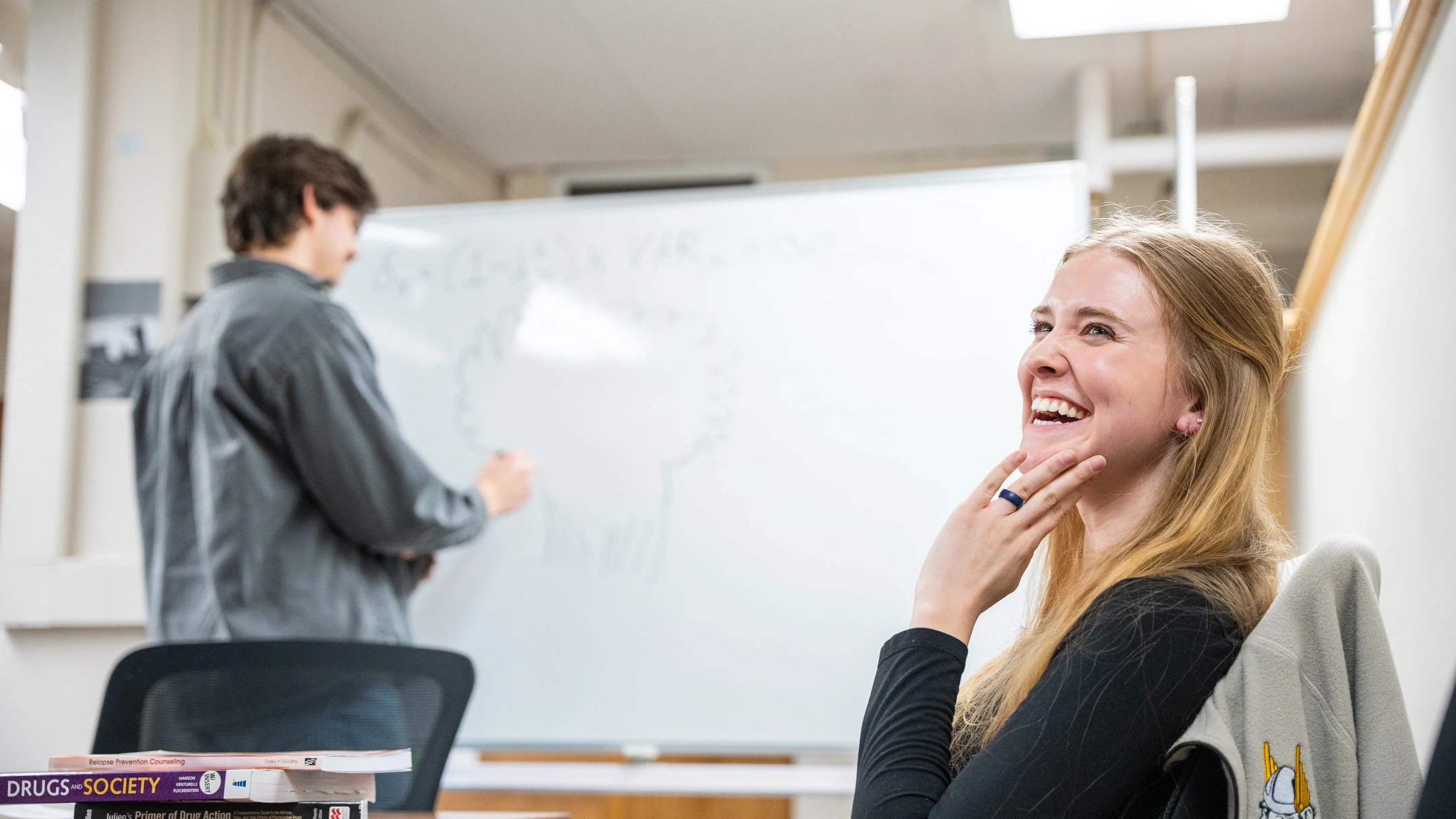 Graduate student Wade Scott at a white board in the Department of Psychology and Communications collaborates with student Katelynn Kjorness while researching addictions.