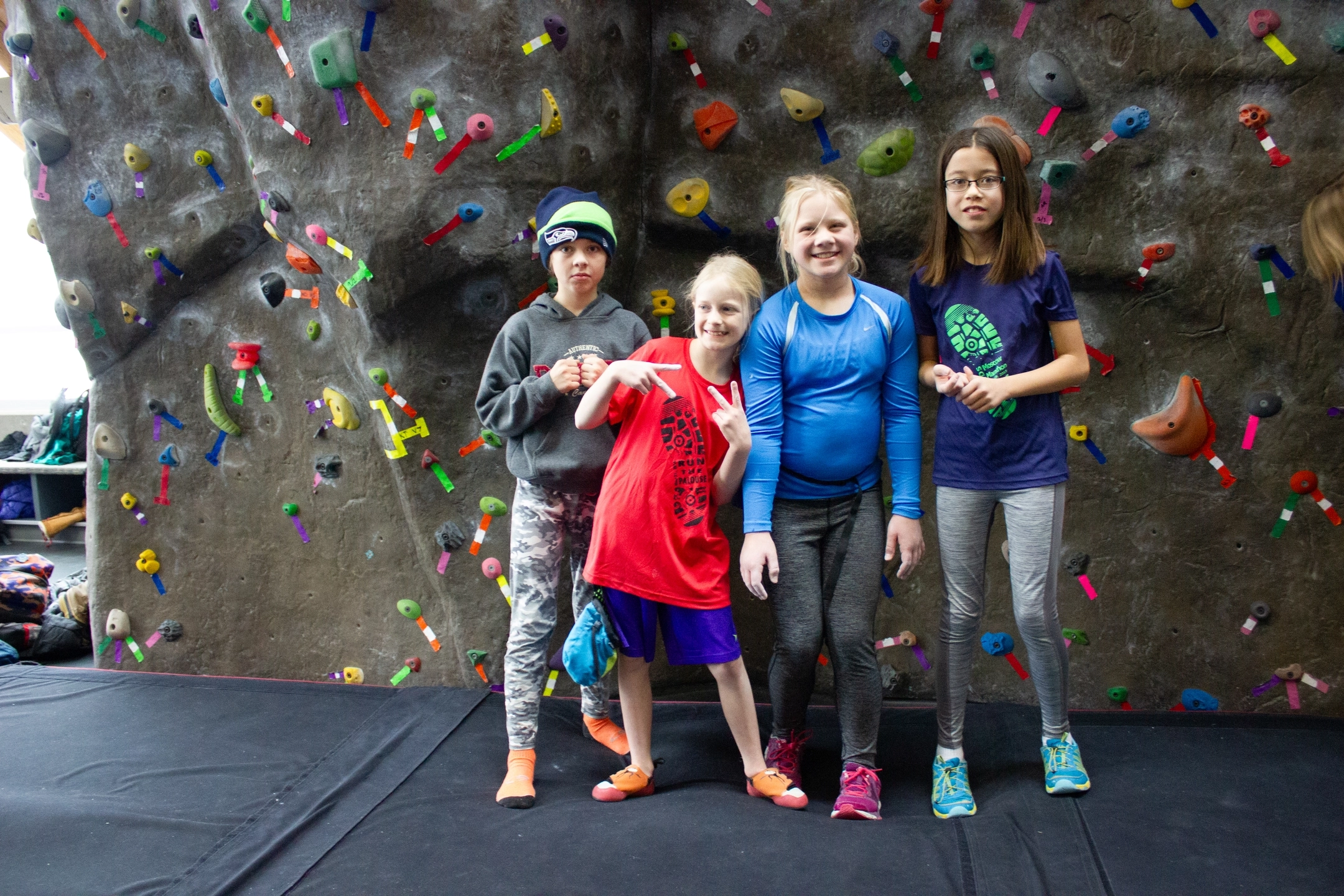 Four kids standing in front of a rock wall
