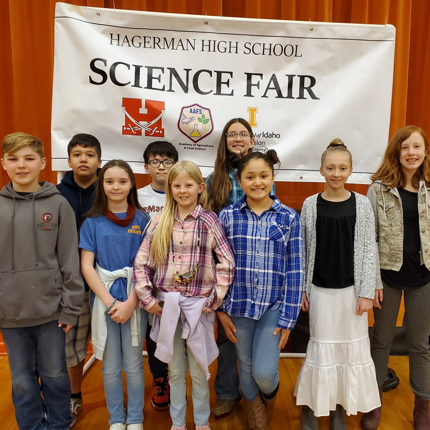 Children stand in front of Science Fair banner