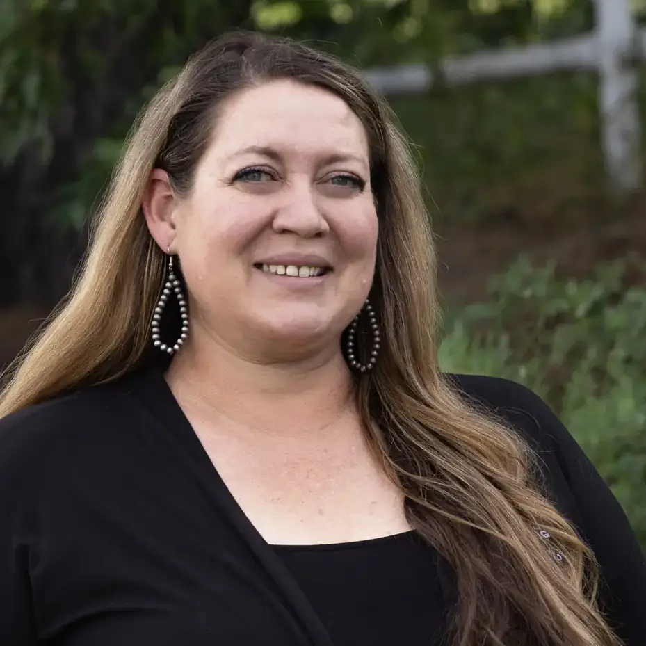 Kasee Smith wearing a black top and greenery in the background
