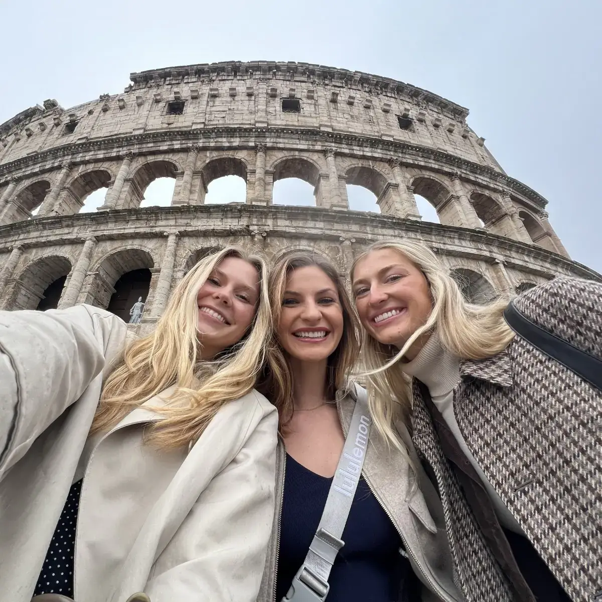 Three women posing in front of the Colosseum.