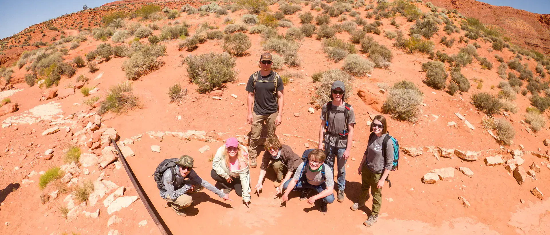 A group of people standing together in the sunny desert.