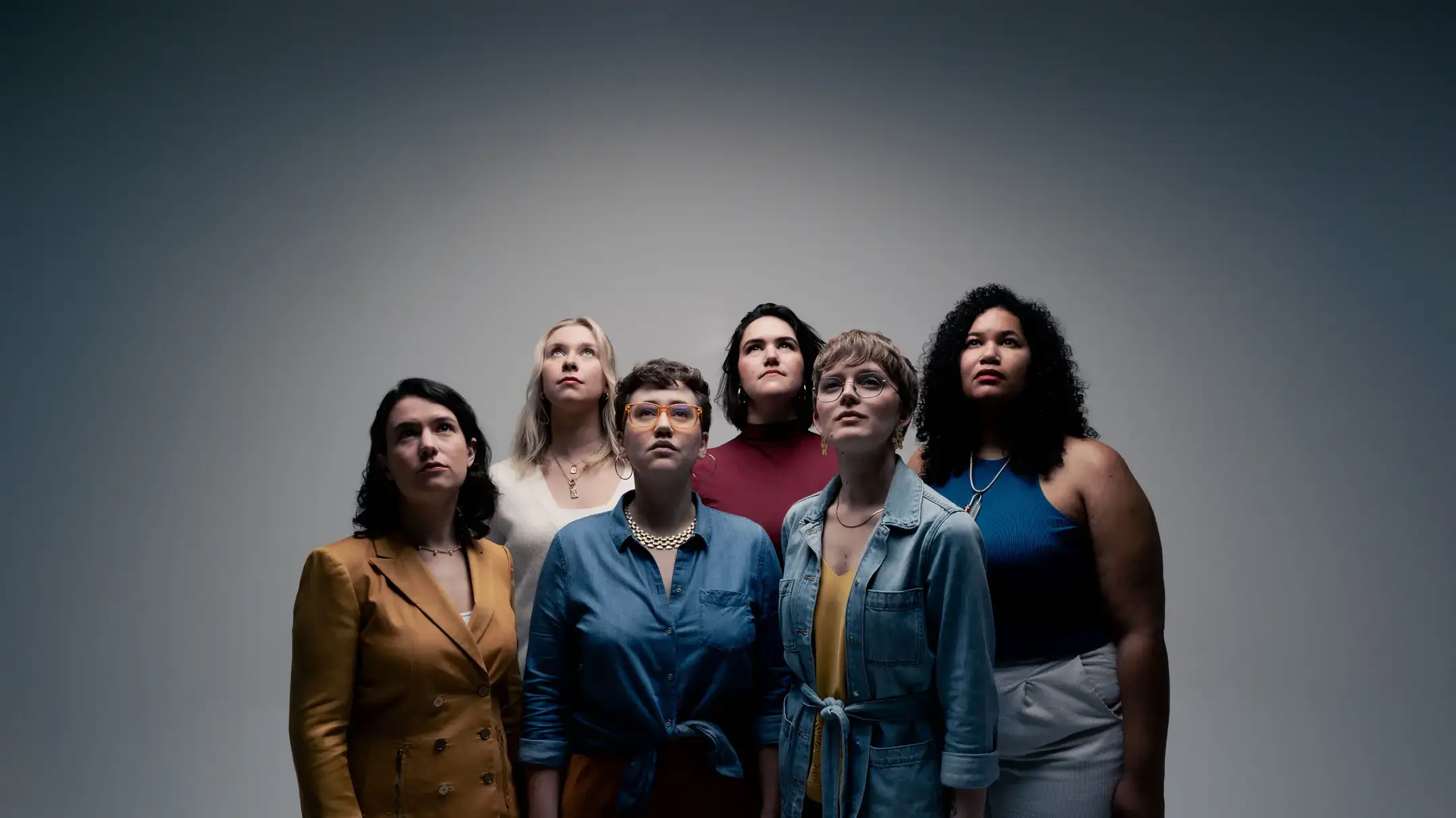 The six women who make up the group Lyyra stand in front of a gray background.