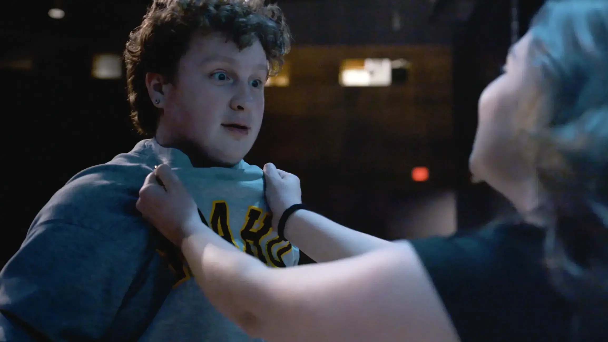 An actor pulls on the shirt collar of another actor.