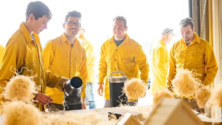 Students work at a designated test area to observe and test a model that replicates wildfire behavior