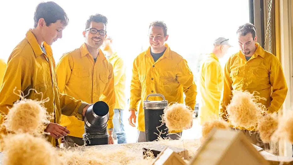 Students work at a designated test area to observe and test a model that replicates wildfire behavior