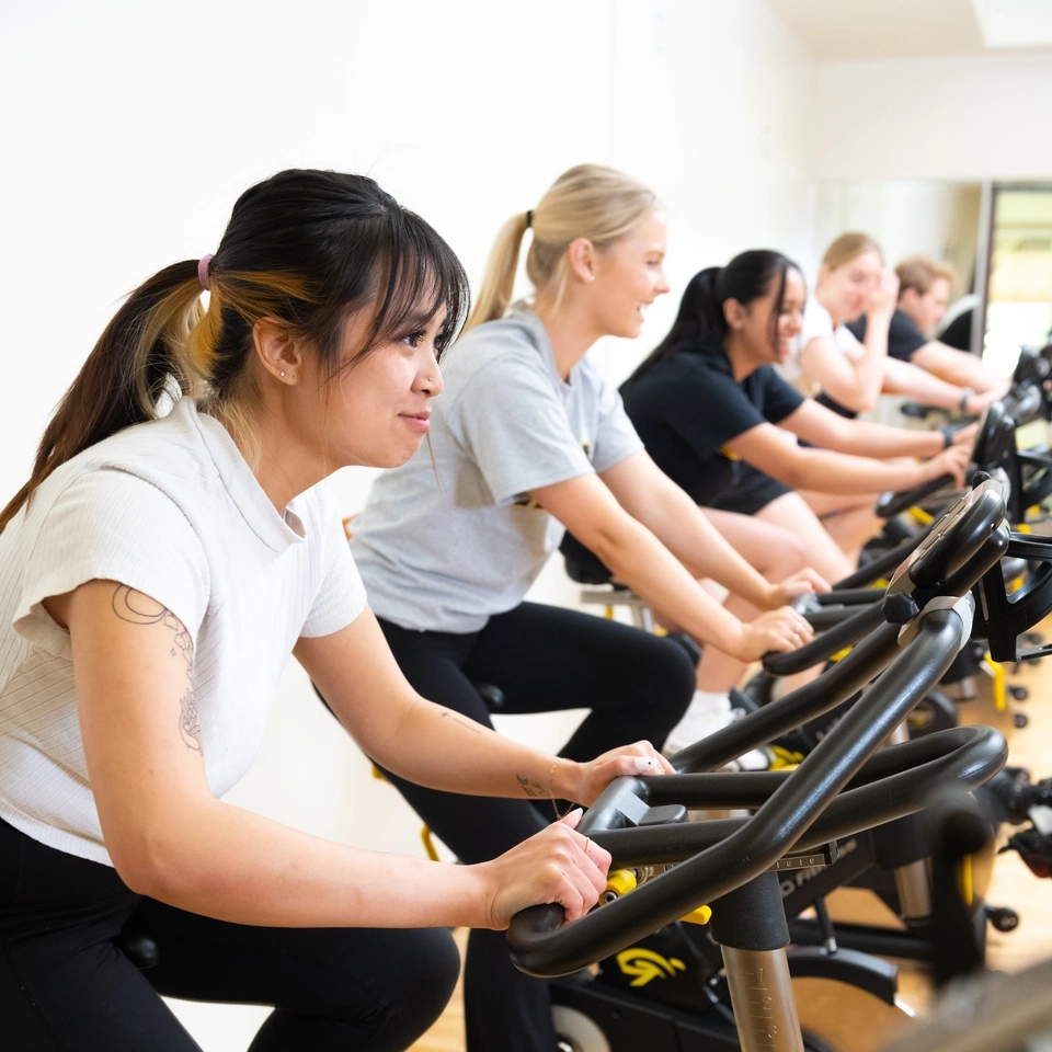 Students pedal on stationary bikes as part a spin class